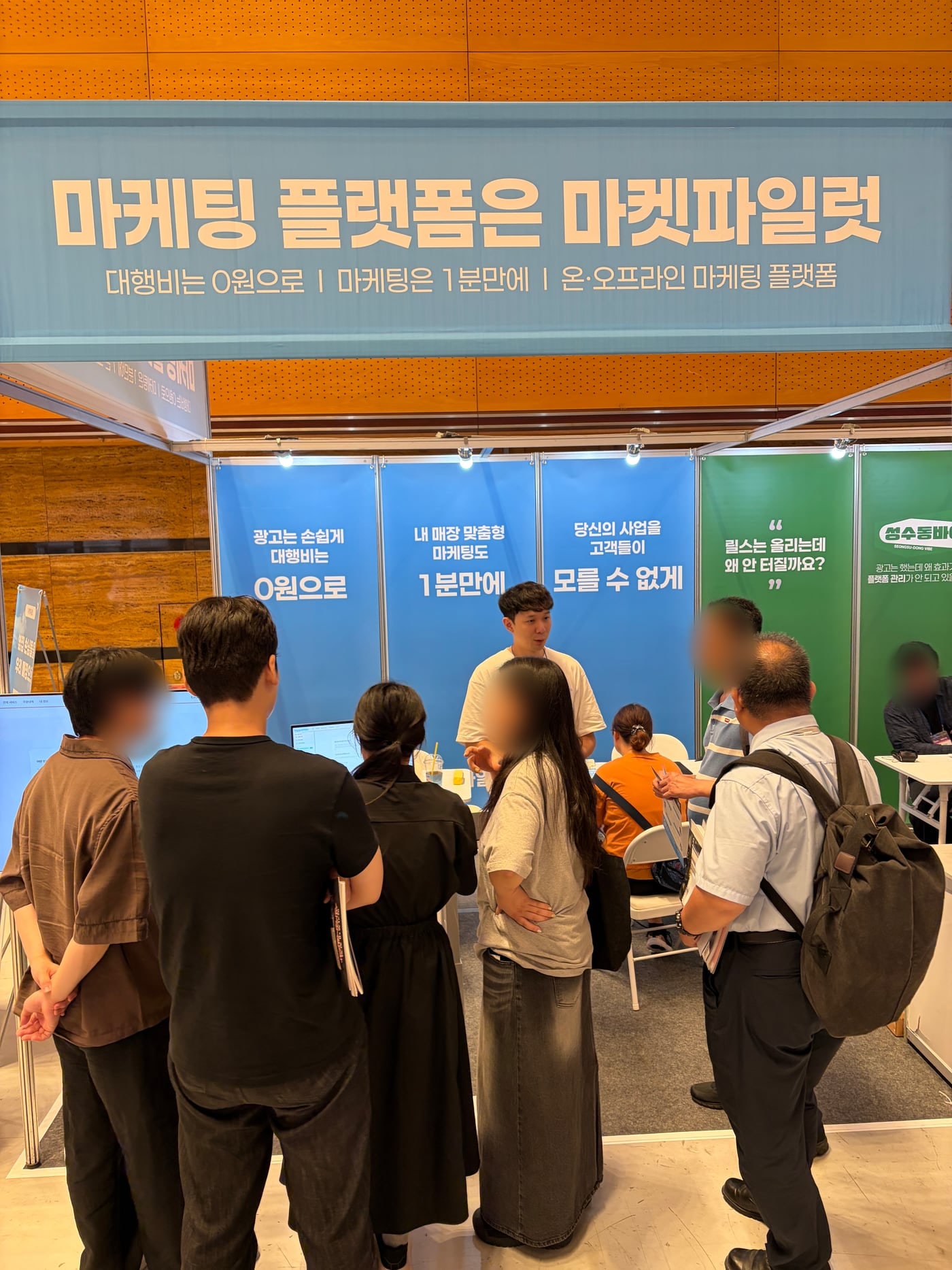 사람이 몰린 시간대의 부스 앞에서 직원 설명을 듣는 관람객들(관람객 얼굴은 흐리게 처리)
